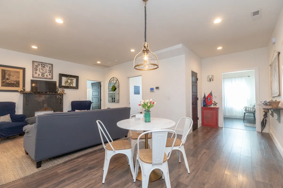 The image presents a cozy round dining table adjacent to a blue sofa and striking wall art, creating an inviting area for casual dining, playing games, or relaxing together. The setup encourages social interaction and makes it easy for groups to gather and celebrate milestones.