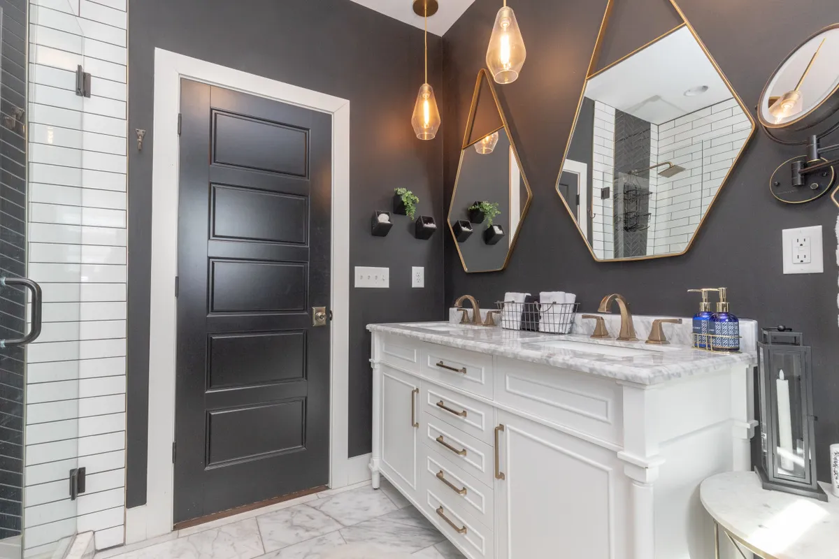 A luxurious bathroom with a marble-topped vanity, gold-framed mirrors, and hanging pendant lights. The sophisticated decor creates an inviting space for morning routines or evening relaxation.