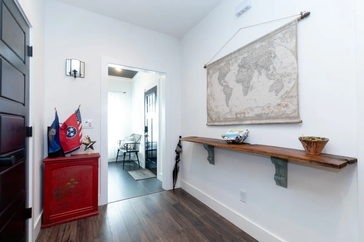 This image captures a welcoming entryway with a world map on the wall, a bold red storage cabinet, and a wooden shelf for essentials. The space is tidy and inviting, creating an immediate sense of arrival and adventure.
