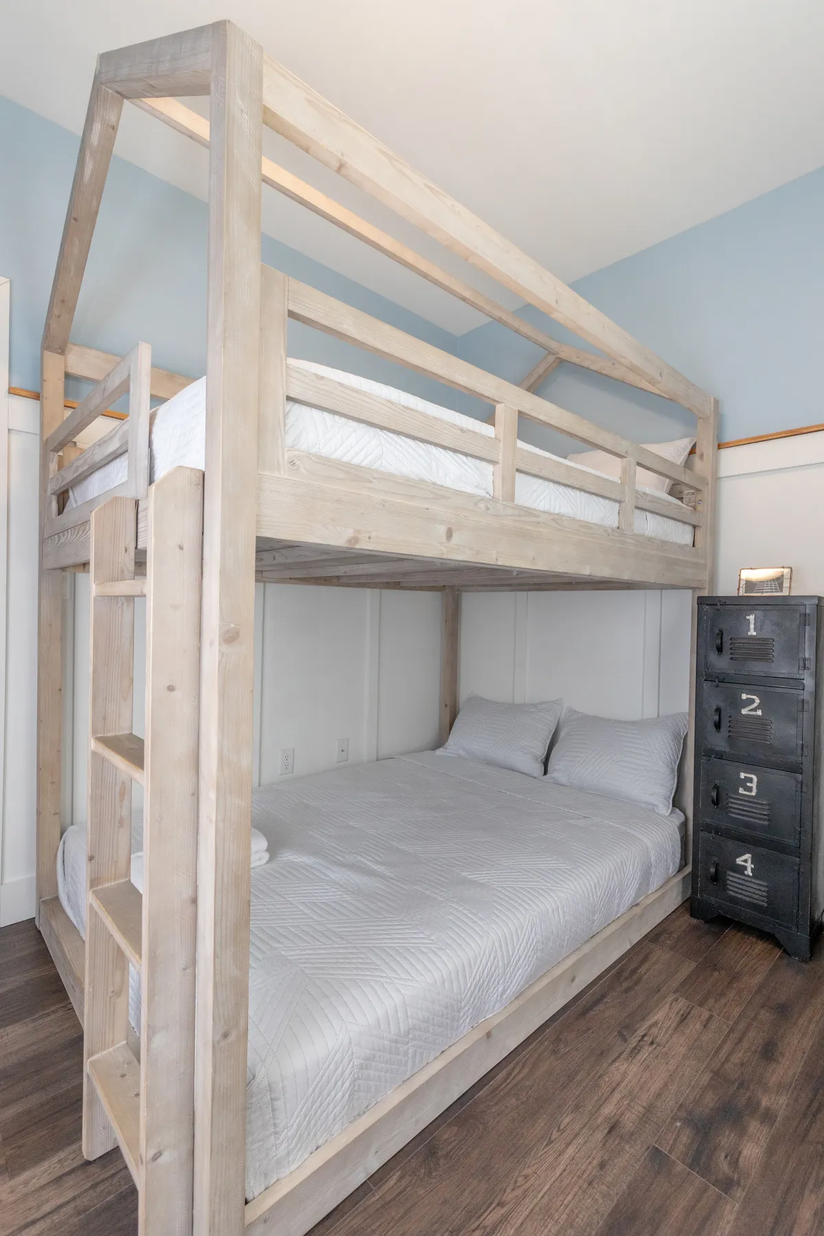 This cheerful bedroom scene showcases a bunk bed with a sturdy wooden ladder and ample storage, signaling its suitability for group stays or families. The arrangement is playful yet practical, accommodating multiple guests while fostering a sense of fun and togetherness.